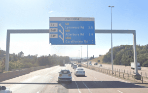 Highway in Pretoria with cars driving under a large overhead sign indicating exits to Lynnwood Rd, Atterbury Rd, and Garstfontein Rd.