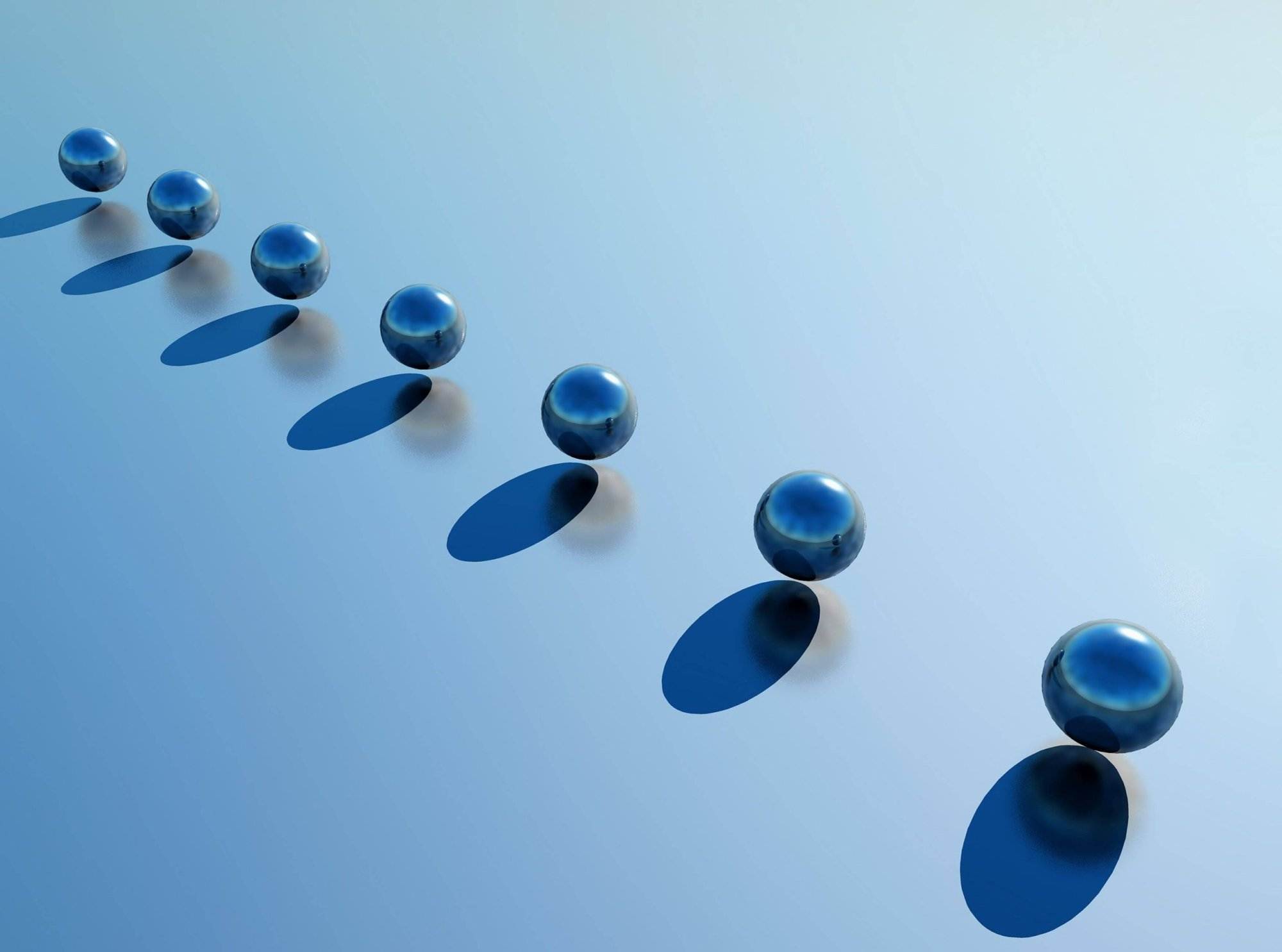 Seven metallic spheres with blue reflections are aligned diagonally on a light blue surface, each casting an oval shadow.
