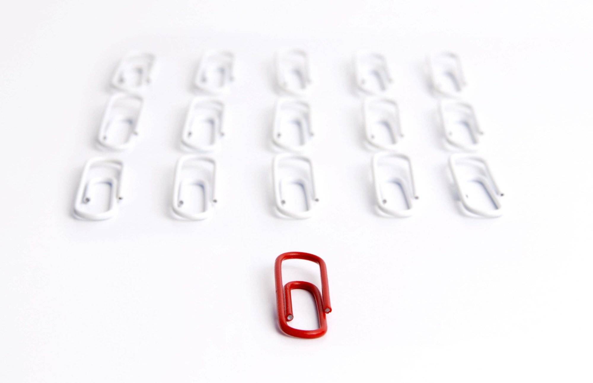 Red clip stands out among a group of white clips arranged in a 4x4 grid on a white background.