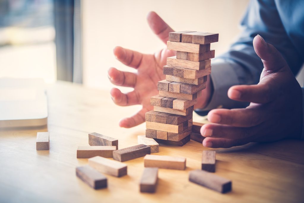 Hands cautiously balancing a wooden block tower, symbolizing business development and strategic planning.