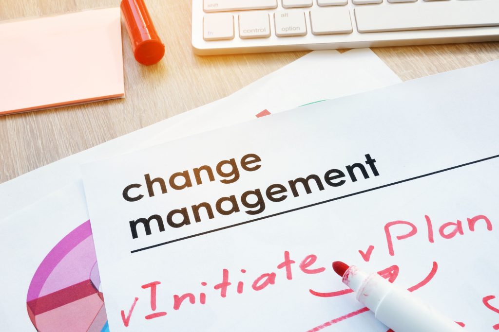 Close-up of a paper titled "Change Management" with a red marker and keyboard in the background.