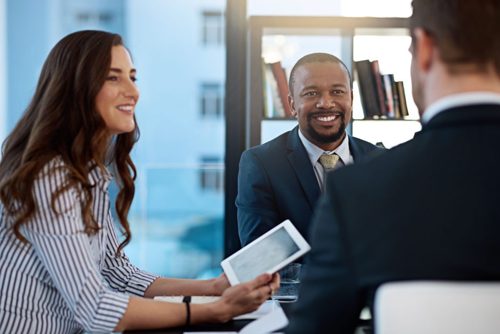 Diverse group in business attire engaged in a meeting, showcasing professional facilitation services in a modern office setting.
