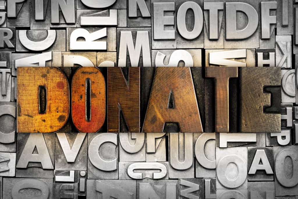 Wooden and metal letterpress blocks spelling "DONATE," highlighting the concept of donations for NPO consulting services.
