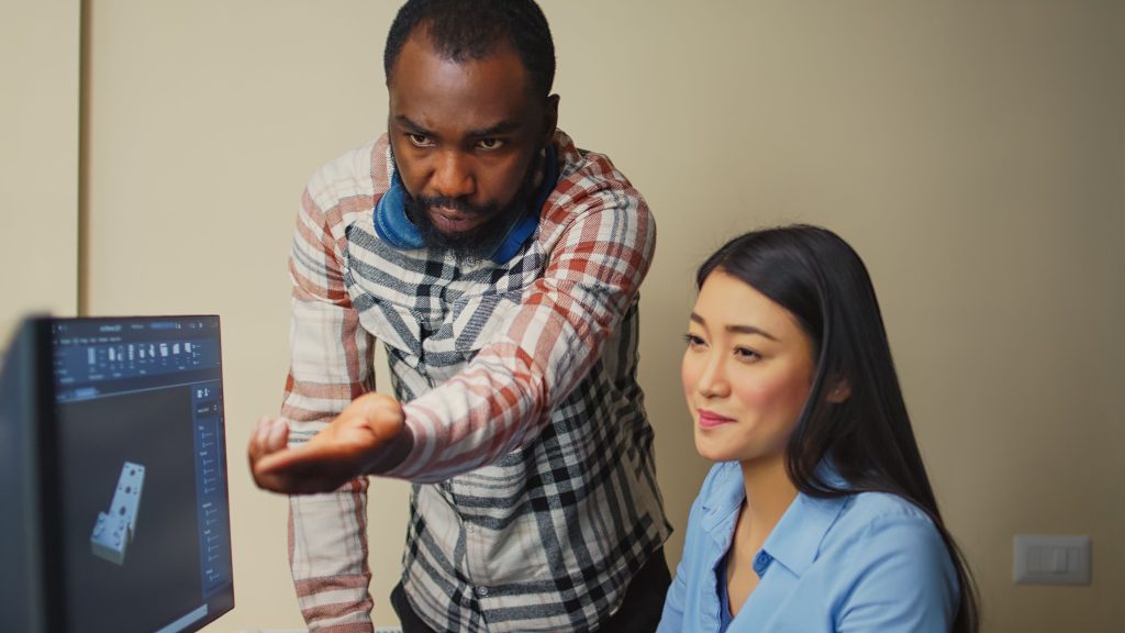 Two colleagues discussing performance management while reviewing data on a computer screen in an office setting.