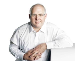 Experienced business coach Daniel Esterhuizen, management consultant, in a white shirt, smiling against a white background.