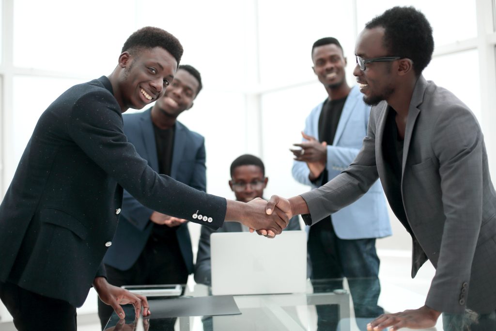 Colleagues shaking hands and smiling, symbolising successful team conflict resolution in a modern office setting.