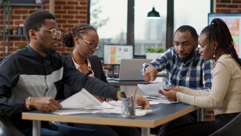 Team discussing Enneagram coaching strategies with documents in a modern office setting.