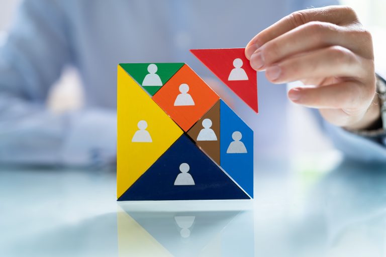 Hand placing a red piece in a puzzle with icons, symbolizing succession planning strategy.