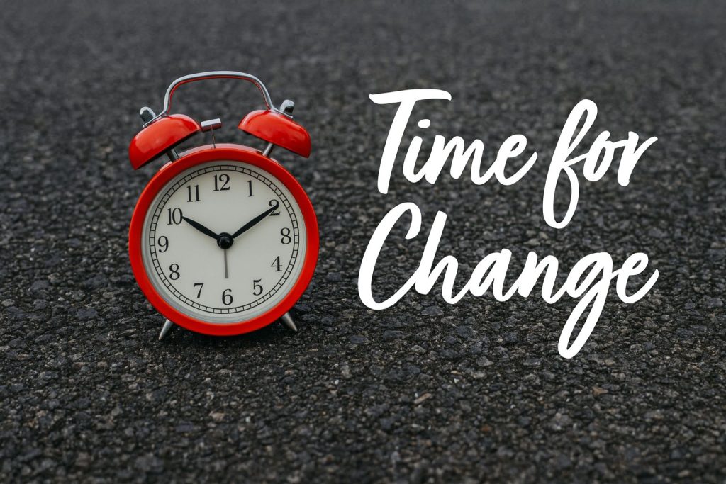 Red alarm clock on asphalt with text "Time for Change," symbolizing dealing with continuous change.