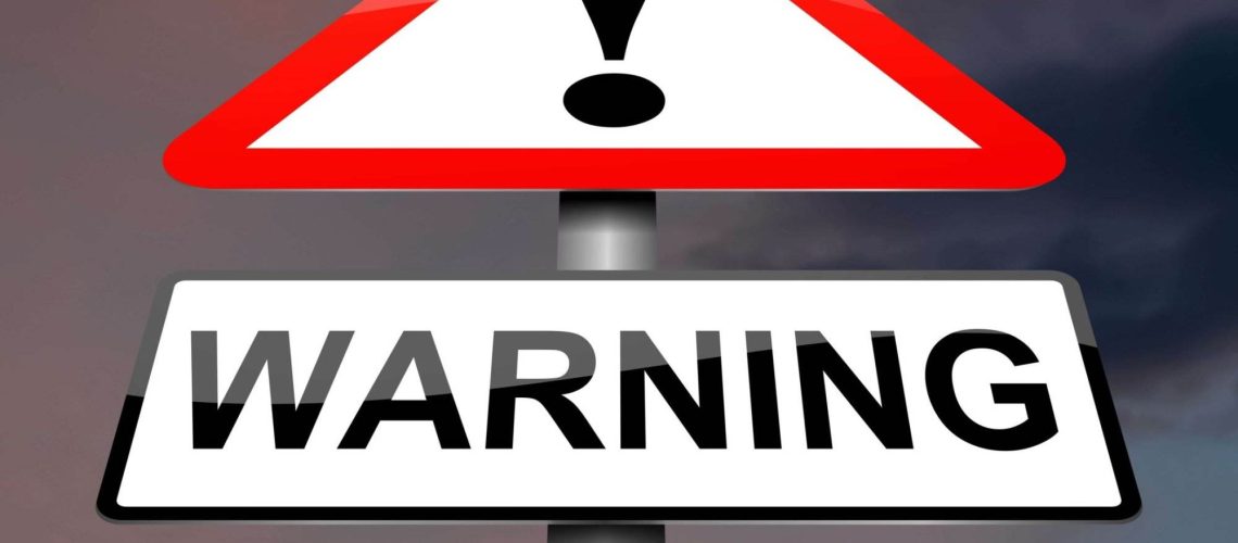 A warning sign with an exclamation mark against a cloudy sky background.