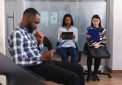 Three people sitting with notes, engaging in career coaching session in a modern office setting.