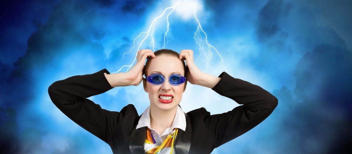 Person in a suit and colorful scarf, wearing blue goggles, holds head with a grimace, background of storm clouds and lightning.