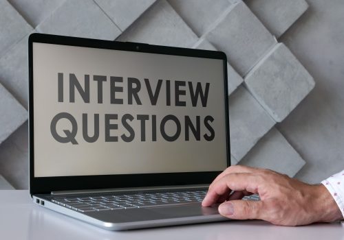 Person using a laptop displaying "Interview Questions," ideal for interview coaching preparation.