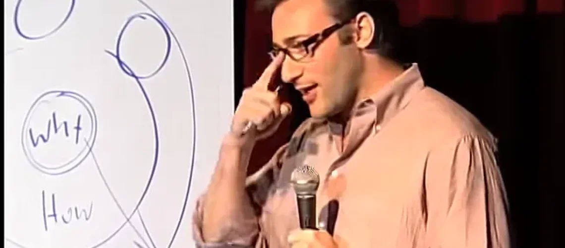 A speaker discusses leadership development and coaching with a diagram showing purpose on a flipchart.
